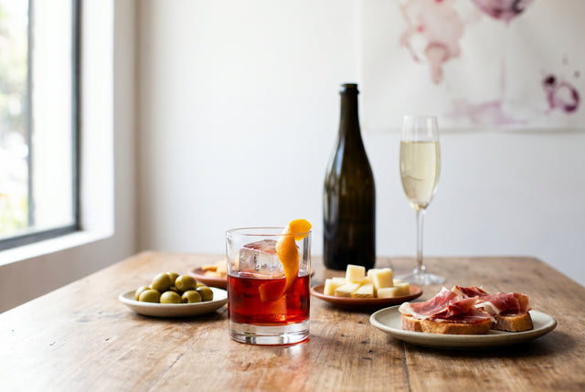 Vermut rojo con hielo, piel de naranja, aceitunas y tapas en una barra luminosa de Lima