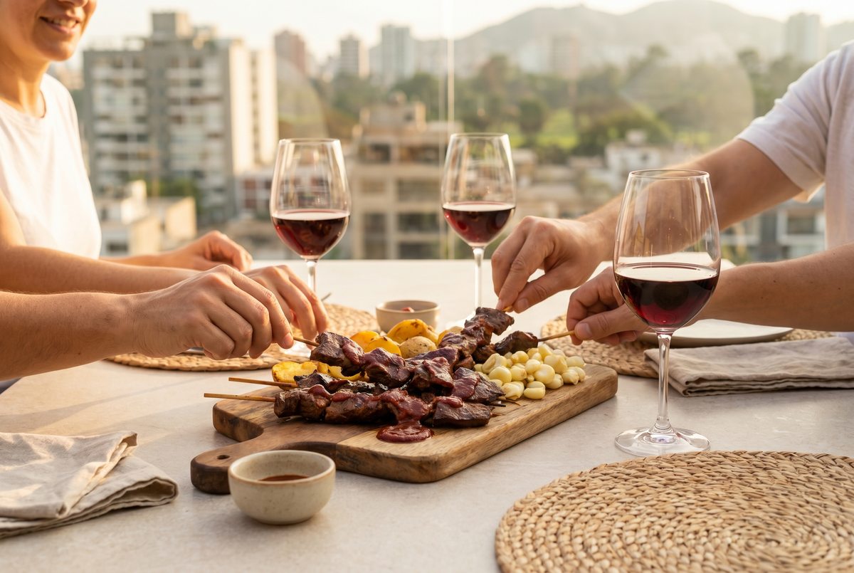 Anticuchos peruanos recién asados junto a copas de vino tinto en una mesa luminosa de Lima